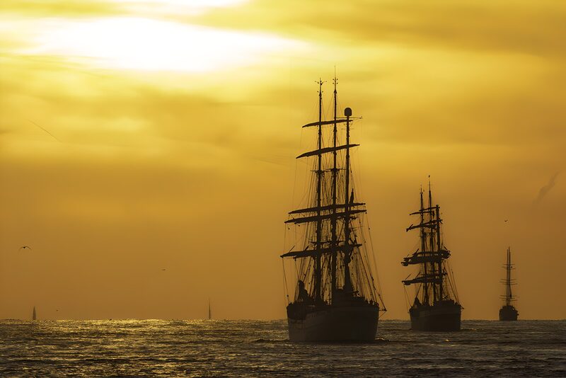 Zeilschepen tegen een zonsondergang