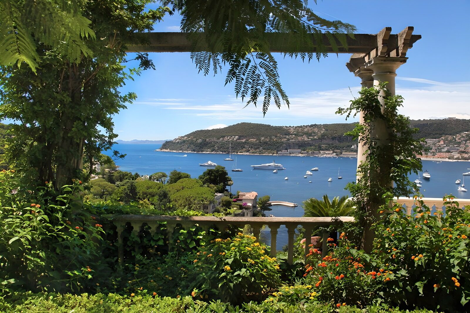Uitzicht vanuit villa tuin op luxe jachtboten