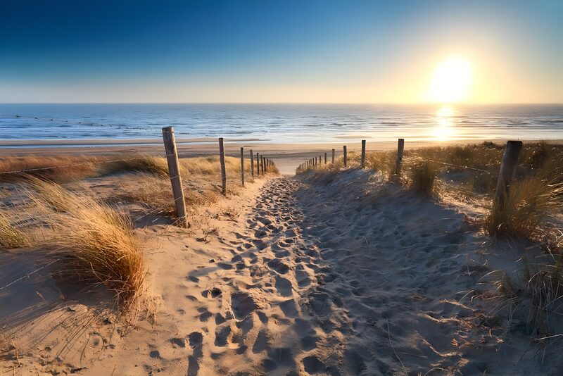 Zandpad naar de zonsondergang aan het strand