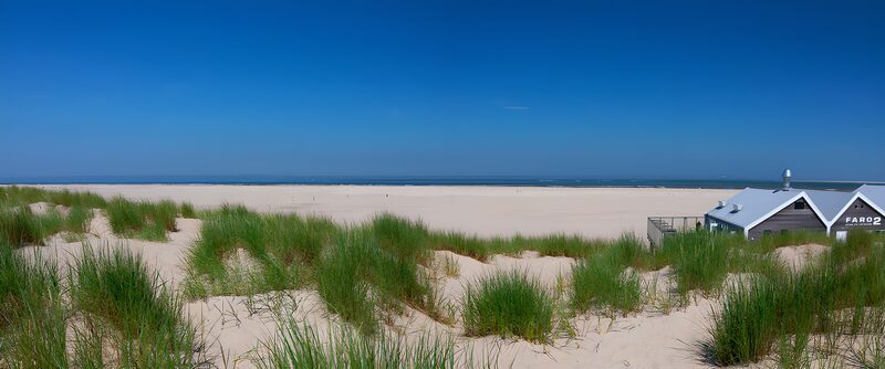 Strand met duinen en blauwe lucht