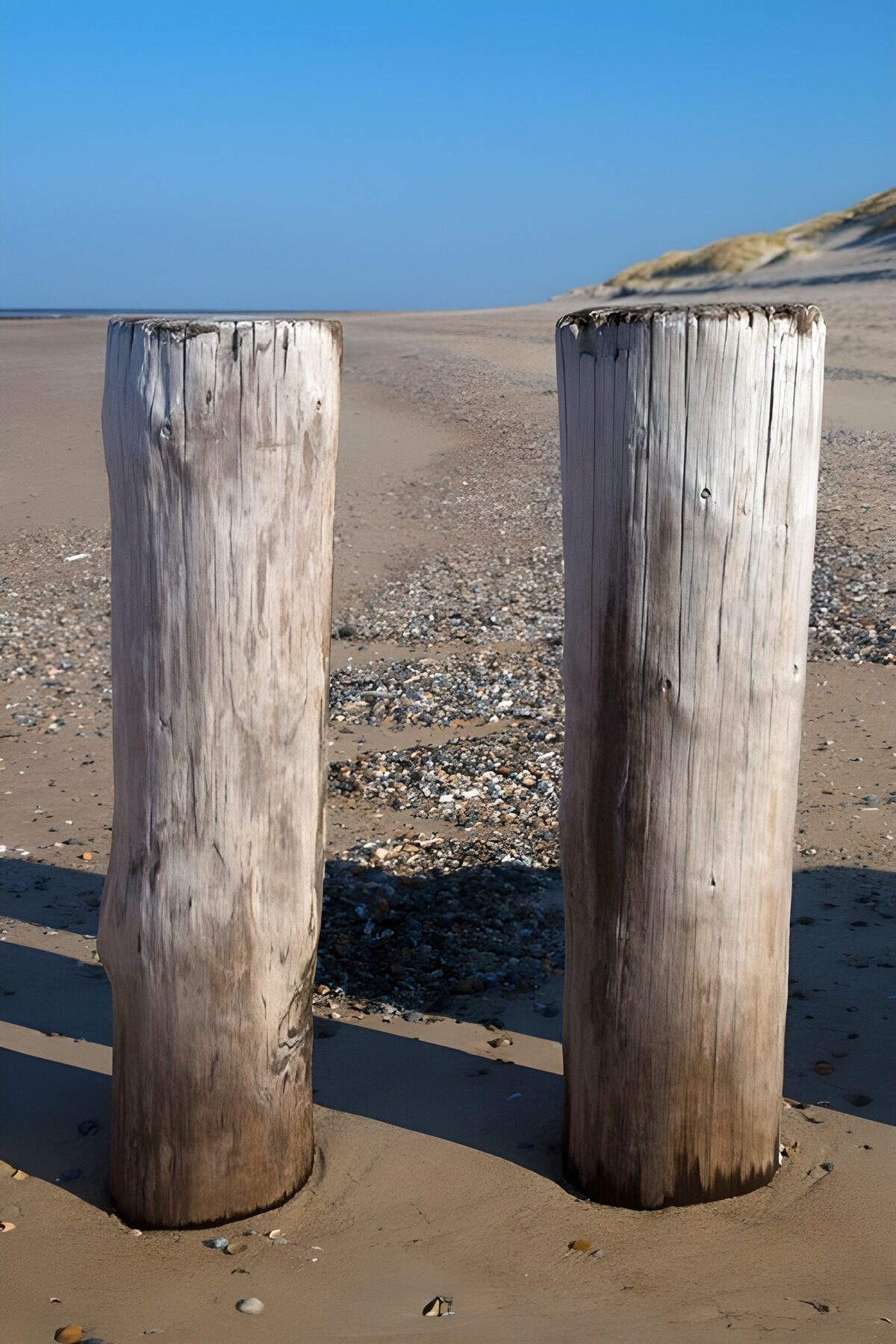 Twee houten palen op het strand