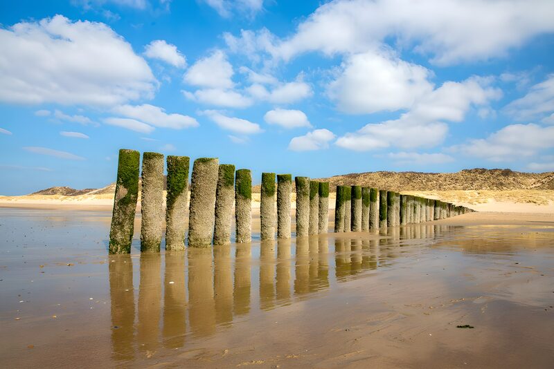 Golven, poelen en palen aan het strand